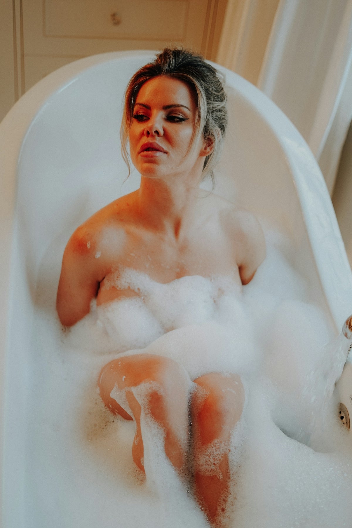 a woman sitting in a bathtub full of foam