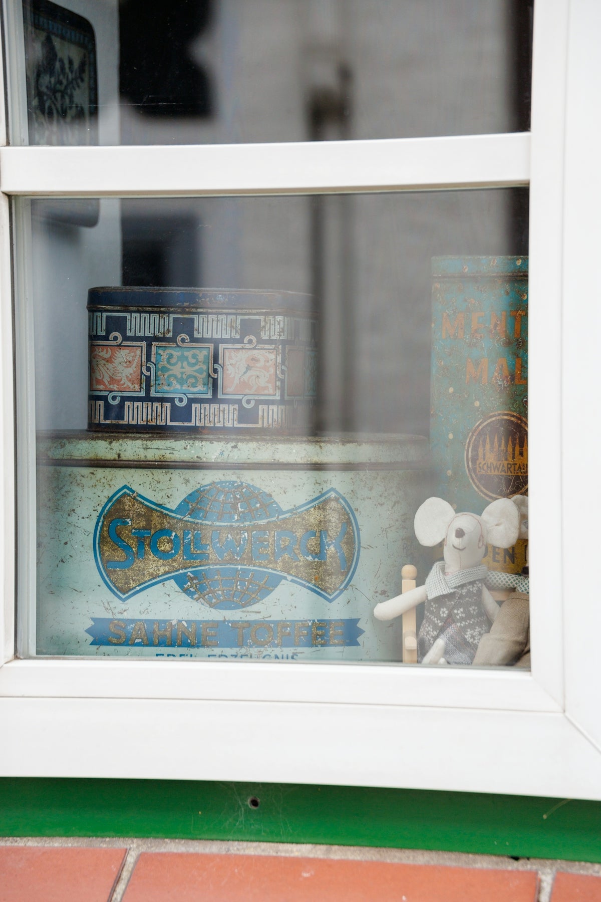 Vintage tins and a stuffed mouse behind glass