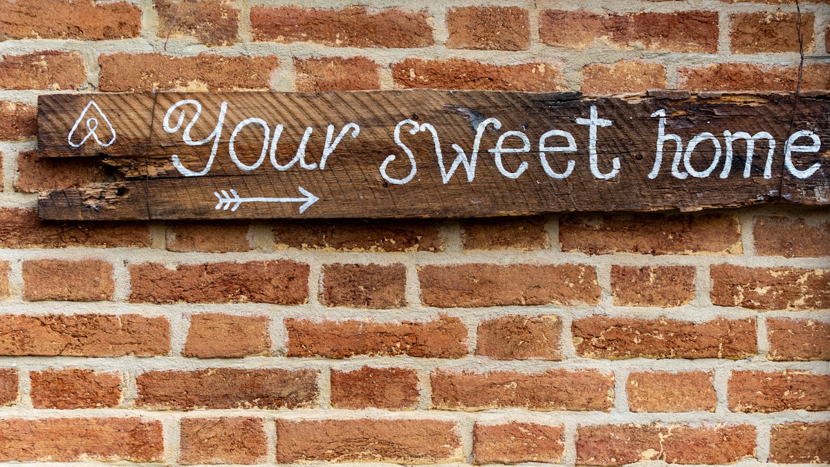 brown brick wall with welcome to the beach signage